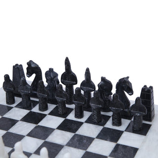 black fancy egyptian chess pieces placing on the white marble chess board